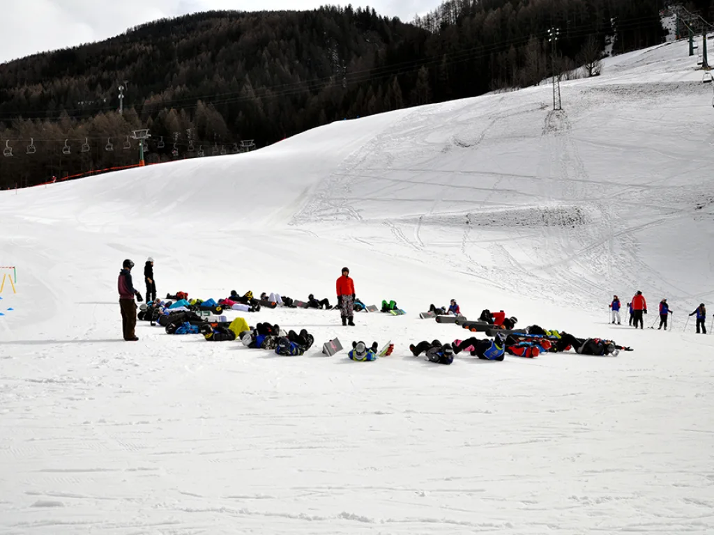 Gruppe liegt und sitzt am Hangfuß im Schnee.
